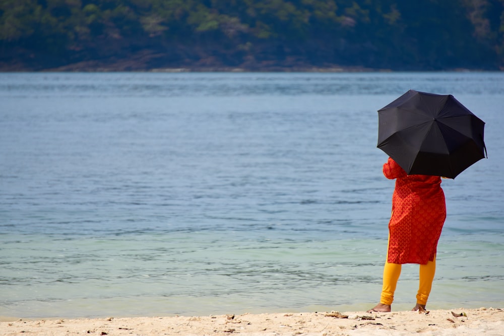 una persona sosteniendo una sombrilla en una playa