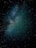 A starry sky with a dense cluster of stars forming a bright region against a dark celestial backdrop. The stars vary in size and brightness, scattered across a deep, dark expanse.