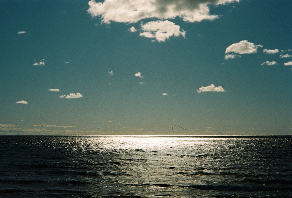 a body of water with a few clouds in the sky