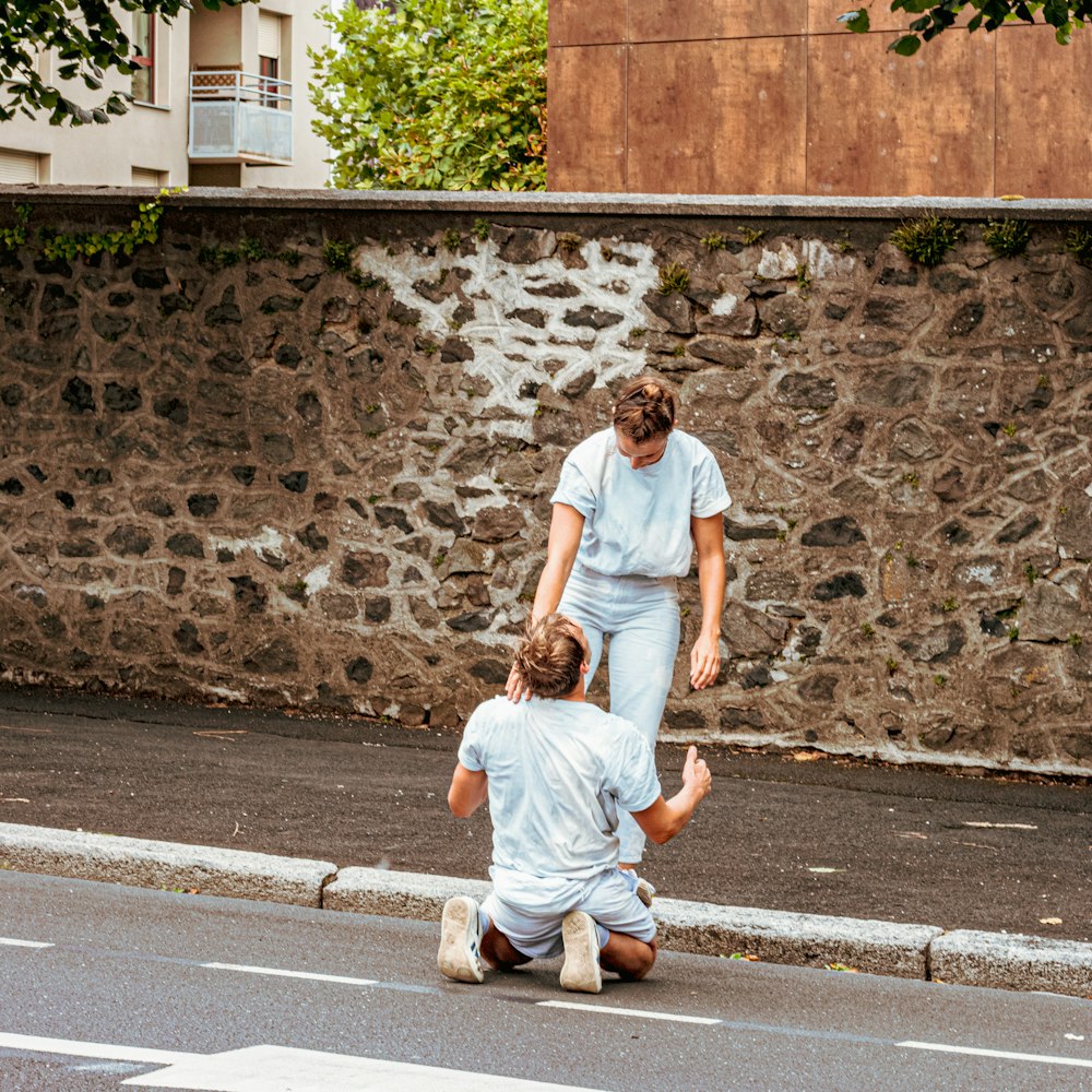 a woman helping a man walk across a street