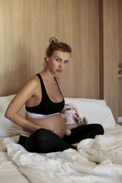 a woman in a black garment and underwear sitting on a bed