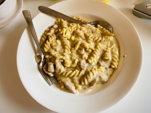 A spoon scooping creamy chicken bacon ranch pasta from the skillet showing tender chicken and bacon pieces