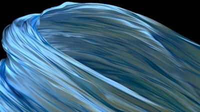 Flowing abstract design featuring smooth, wavy forms reminiscent of fabric or liquid. The surface has a glossy texture with shades of blue and green.