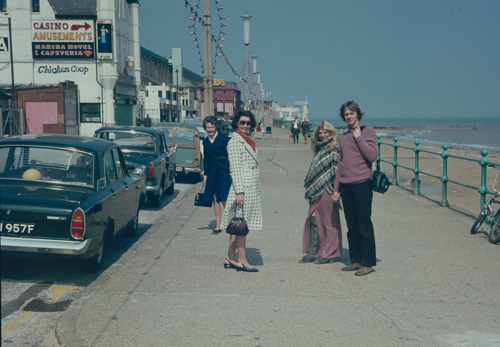 a group of women standing on a sidewalk next to a body of water