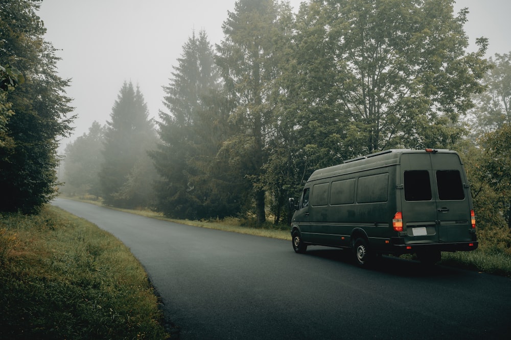 a van on a road with trees on either side of it