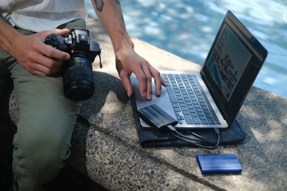a person holding a camera and a laptop