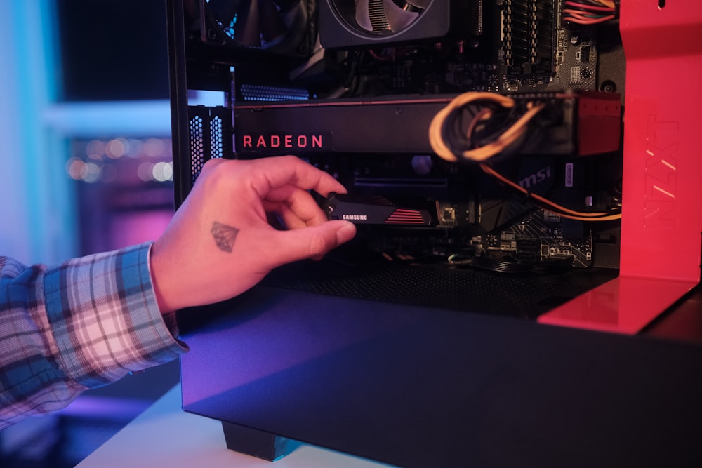 La mano de una persona sobre una mesa con una computadora y cables