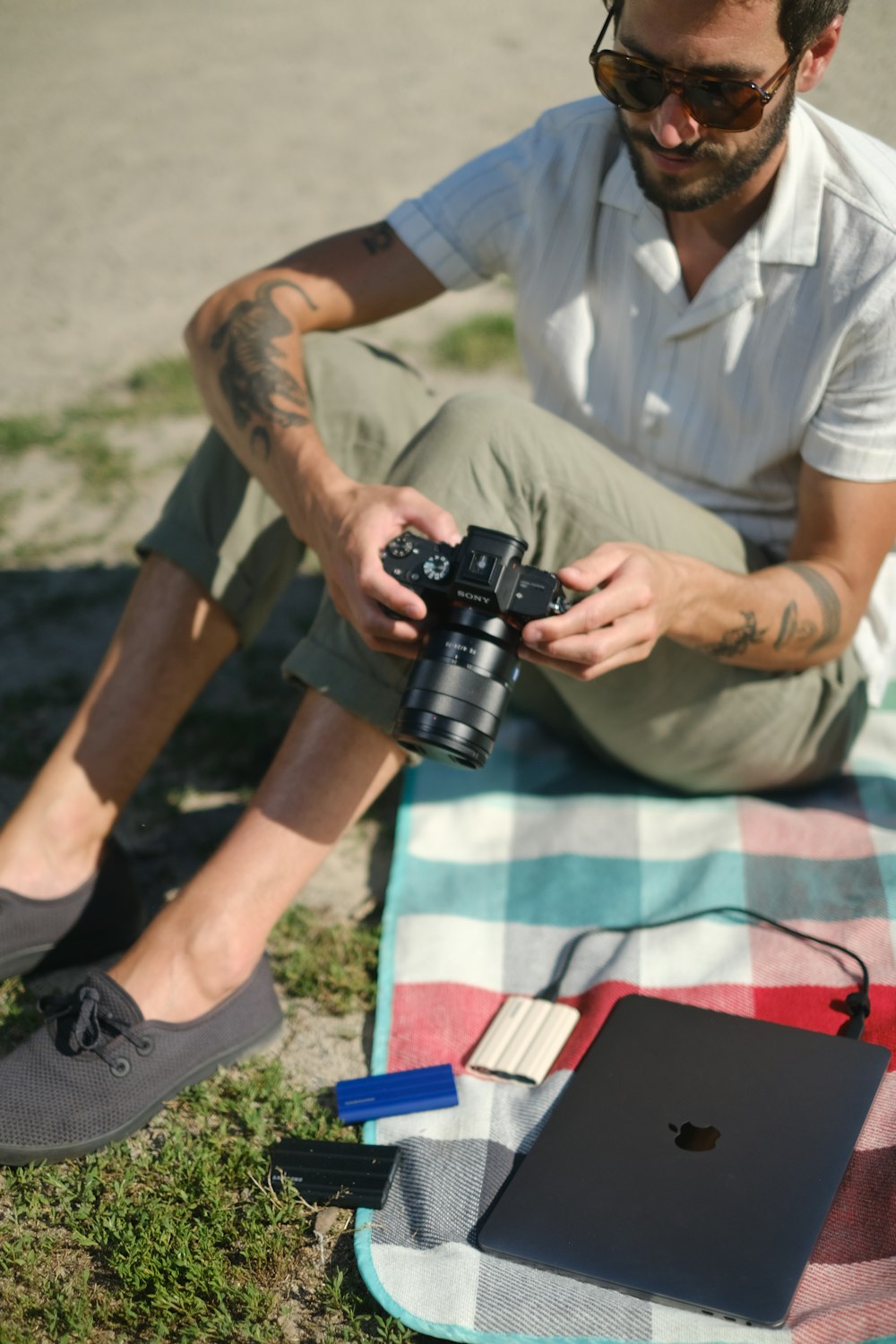 a man sitting on the ground with a camera and a laptop