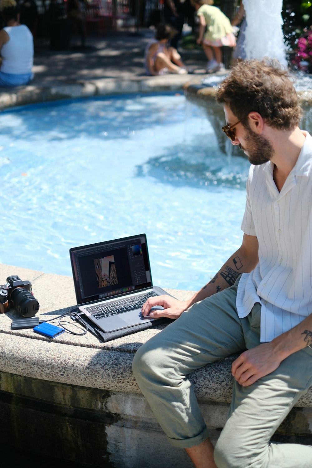 a man sitting on a ledge with a laptop