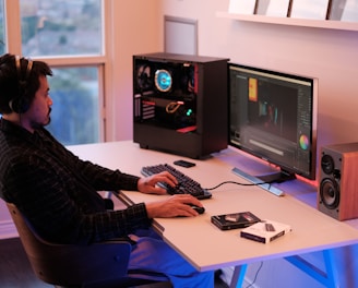 a person sitting at a desk with a computer and speakers