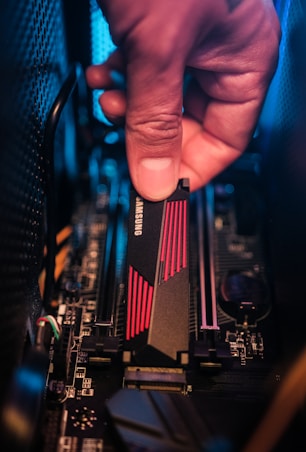 a hand holding a black and red electronic device