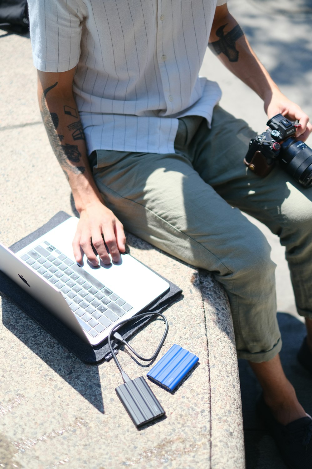 a person sitting on the ground with a laptop and camera