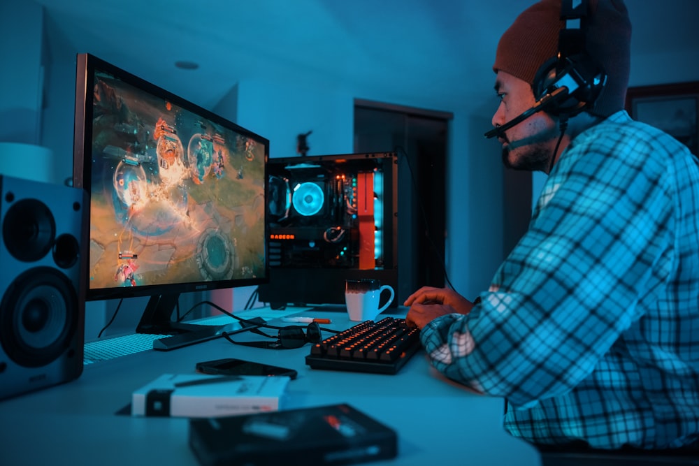 a man wearing headphones and sitting at a desk with a computer