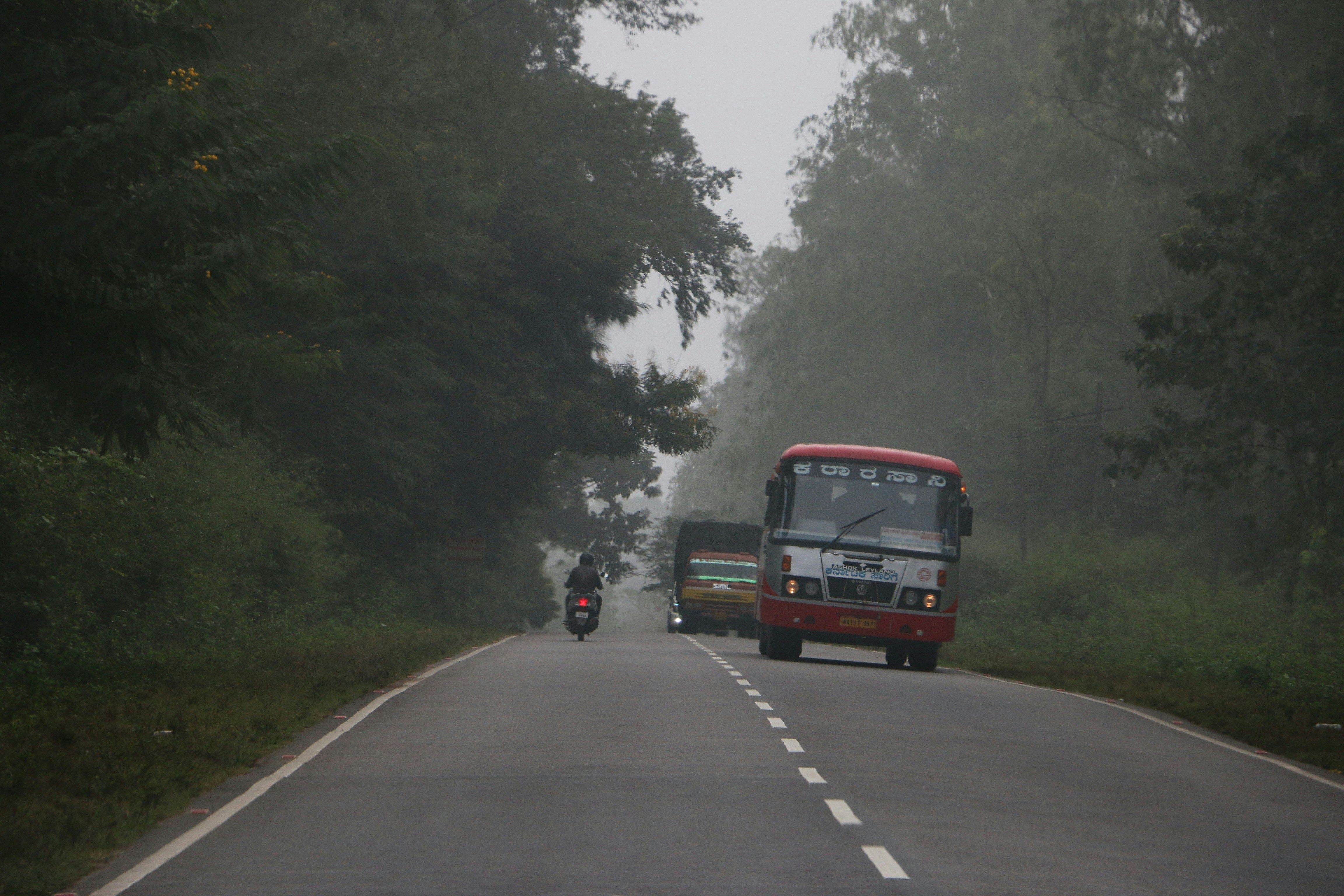 a motorcycle and bus driving down a road