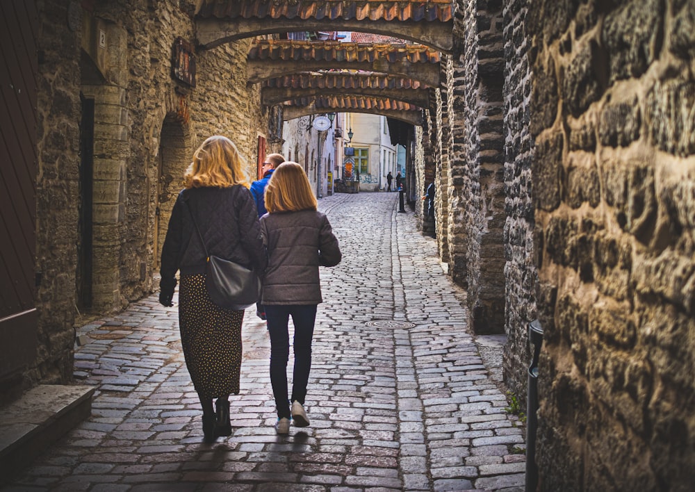 a couple of women walking down a stone street