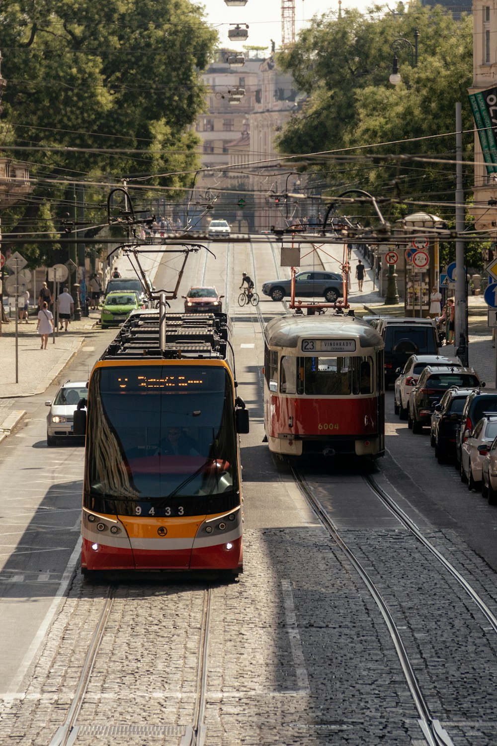 a couple of trolleys on a street with cars and people