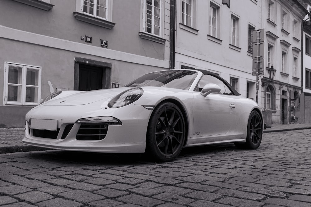 a white sports car parked on a brick road