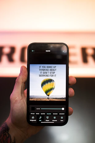 A close-up of a hand holding a smartphone showing a vibrant image with an inspiring life quote.