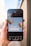 A smartphone held in a hand displays an image editing application featuring a design with two colorful hot air balloons and the phrase 'let's get creative' on a light blue background. The app interface shows various editing options at the bottom, such as styles, text, shapes, and more.