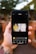 A hand holding a smartphone, displaying an application on the screen. The application showcases a rectangular image of a person standing in front of a waterfall with the text 'Energize your life' in yellow font. The background of the environment is slightly out of focus, featuring greenery and a brick wall.