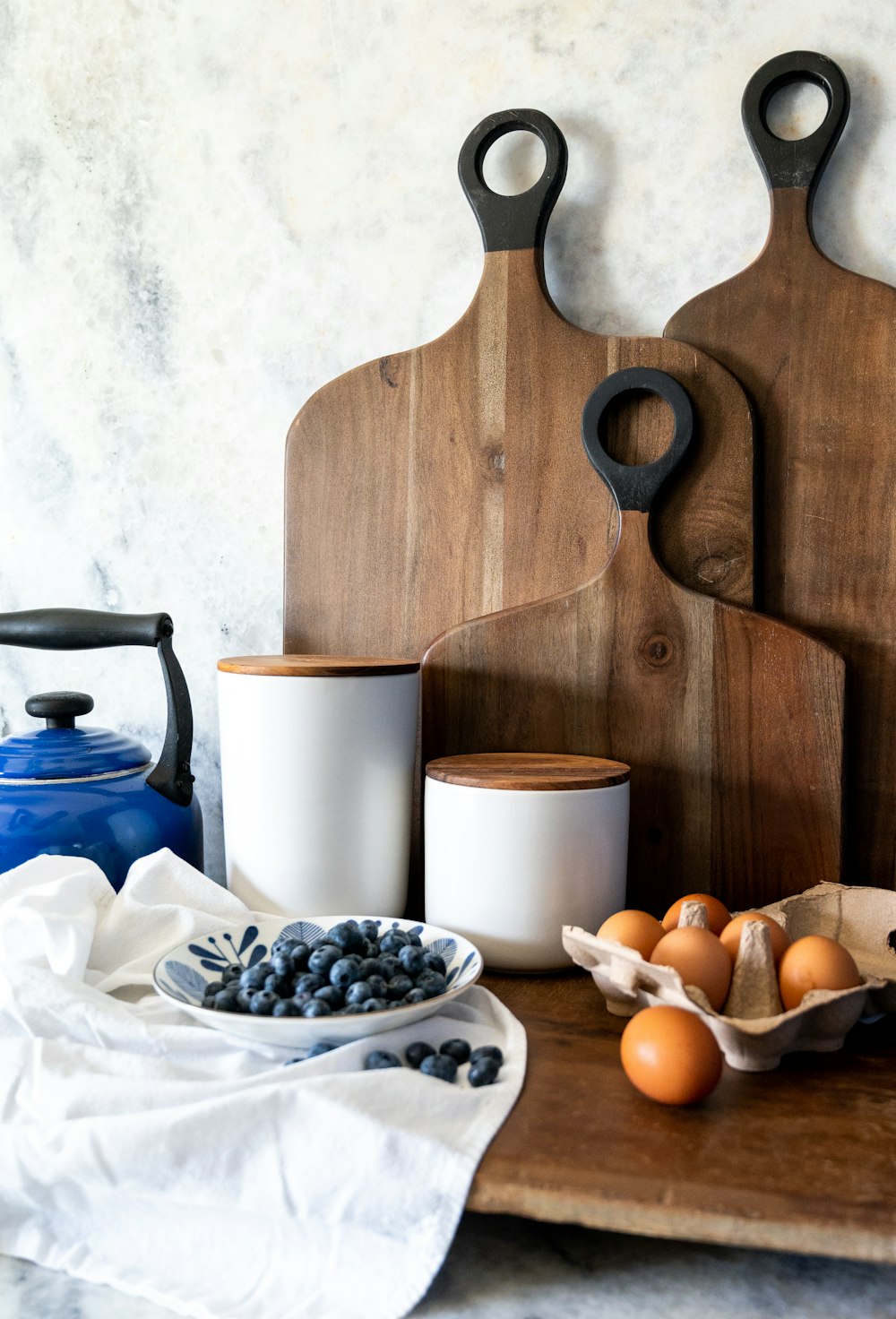 a wooden table with a bowl of eggs and a pitcher and a teapot