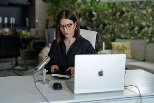 A person sitting at a cozy desk with a notebook and headphones, practicing speaking on a laptop.