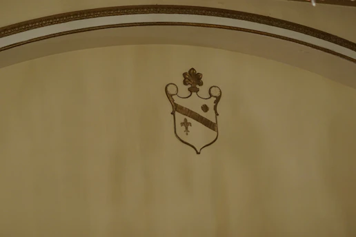 A vintage parchment background softly illuminated by warm brass accents, featuring an elegant shield emblem in faded gold.