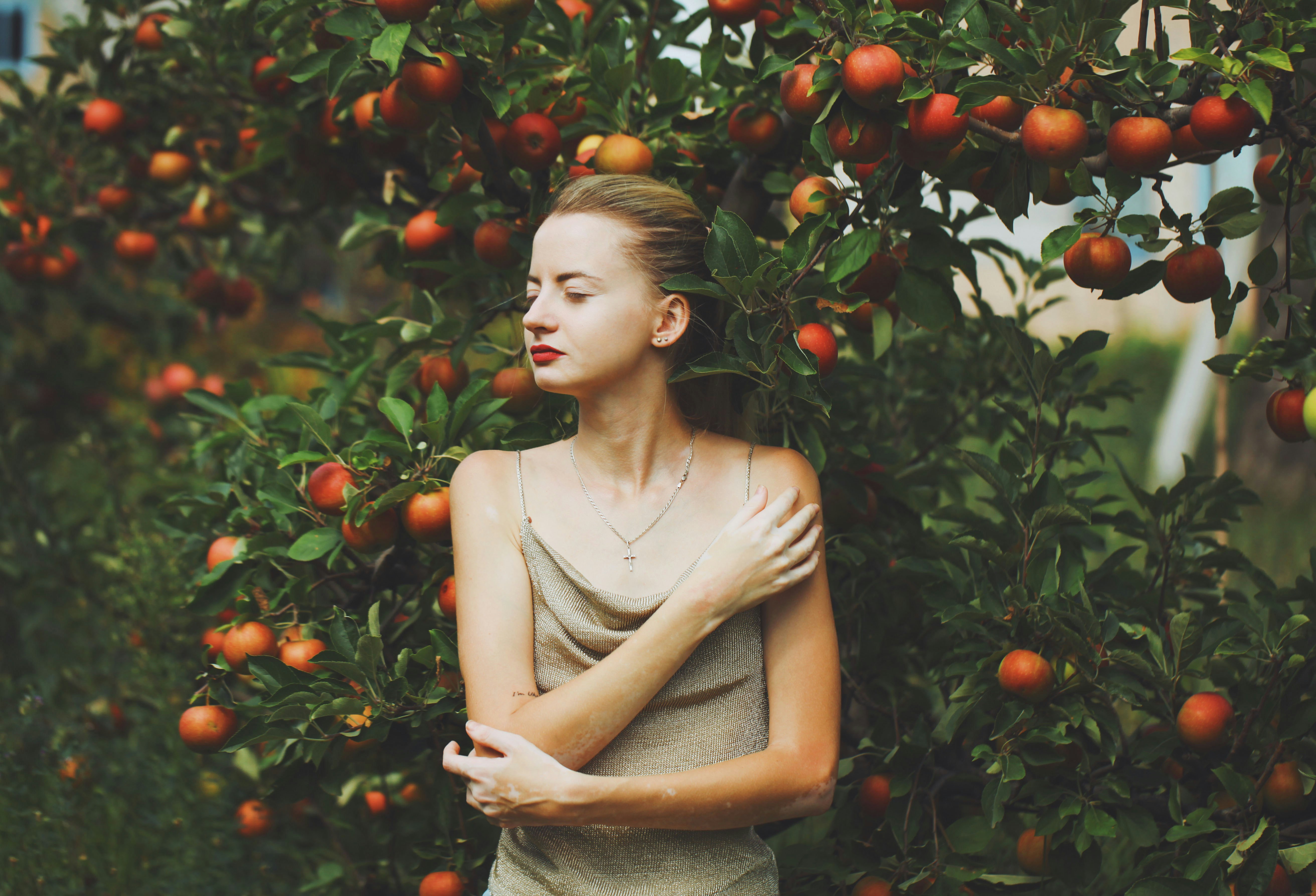 a person standing in front of a tree with oranges