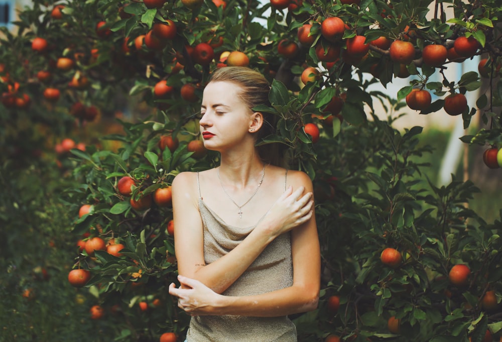 a person standing in front of a tree with oranges