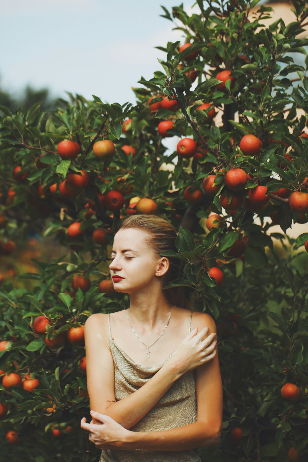 a woman standing in front of a tree with oranges