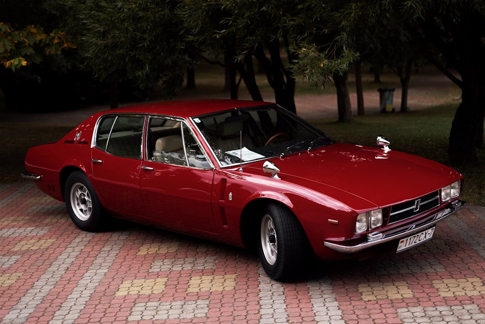 Un coche rojo aparcado en un camino de ladrillos