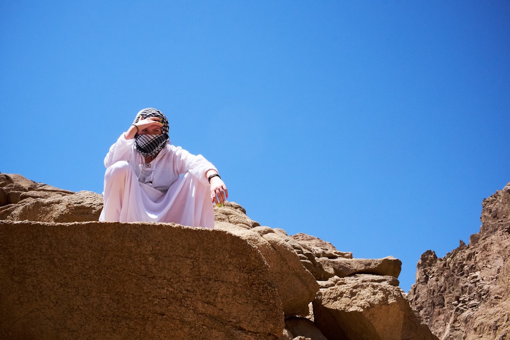 a man in a white robe and head covering standing on a rock