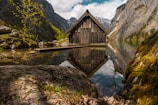 A tranquil lake view with a rustic cabin nearby.