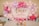 A festive arrangement features pink, purple, and white balloons surrounding a backdrop with 'One Happy Birthday' written in gold glitter letters. Decorations include small butterfly stickers on some balloons and tables laid out with gift bags and jars filled with colorful candies.