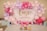 A festive arrangement features pink, purple, and white balloons surrounding a backdrop with 'One Happy Birthday' written in gold glitter letters. Decorations include small butterfly stickers on some balloons and tables laid out with gift bags and jars filled with colorful candies.