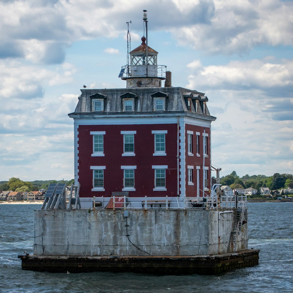 a red and white building on a dock with Thomas Point Shoal Light in the background