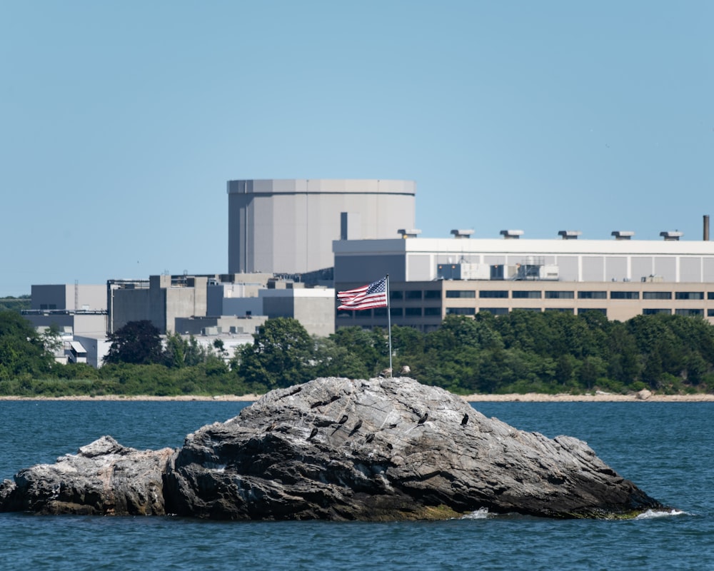 a large building with a flag on top of a rock in the water