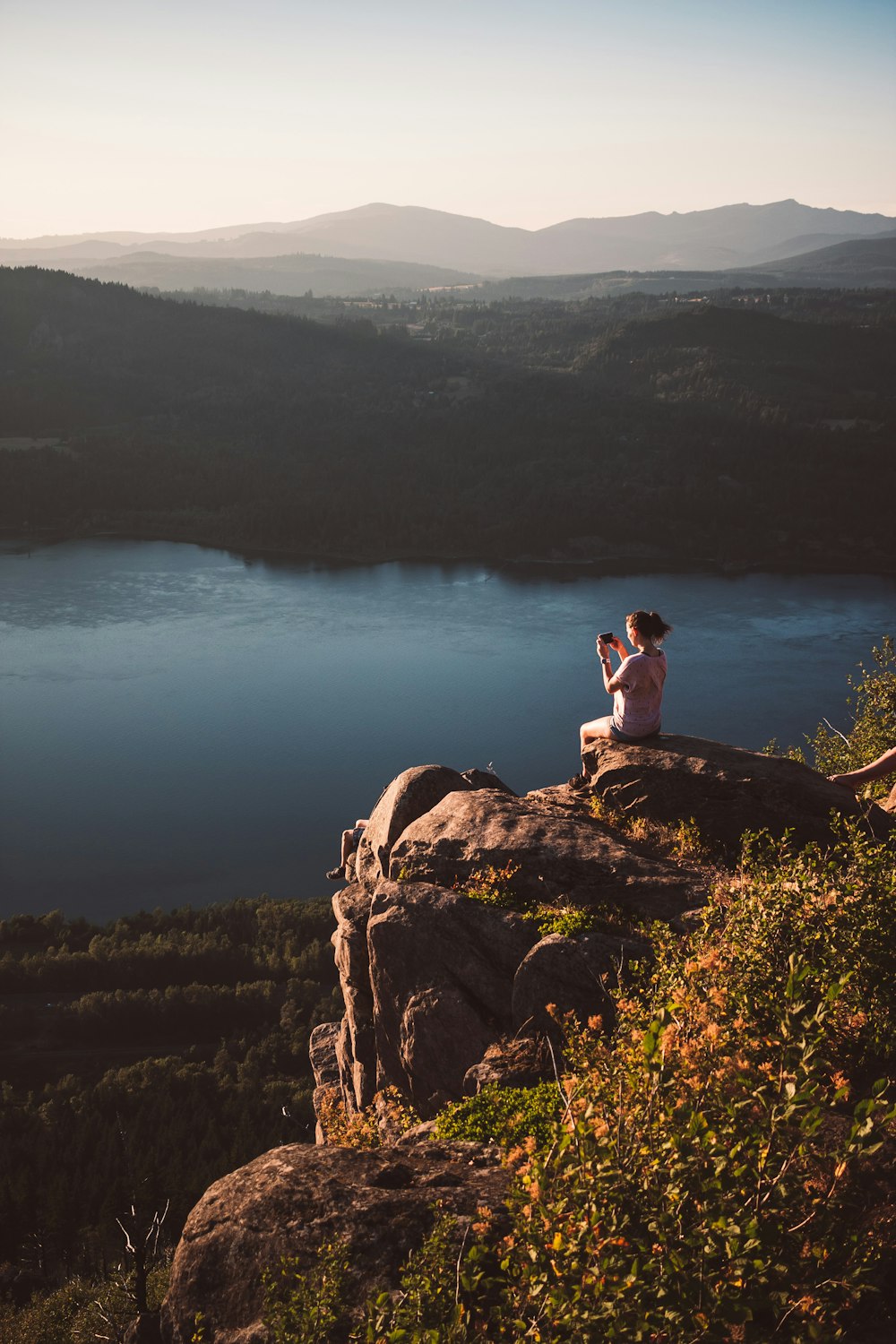 a man sitting on a rock overlooking a body of water