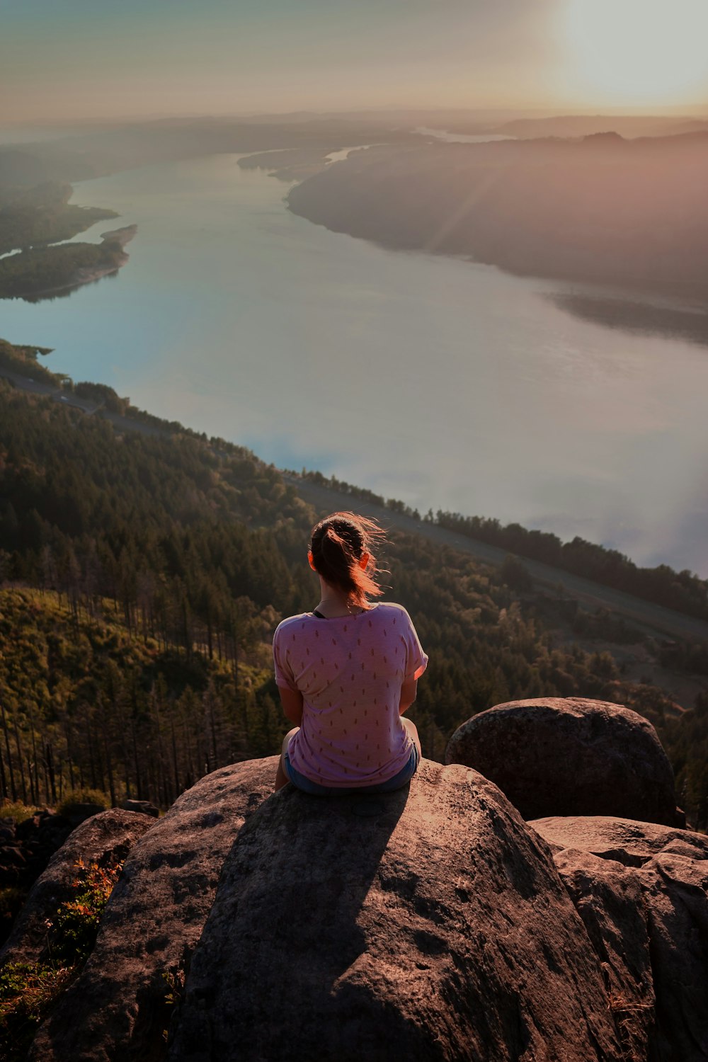 a man sitting on a rock overlooking a body of water