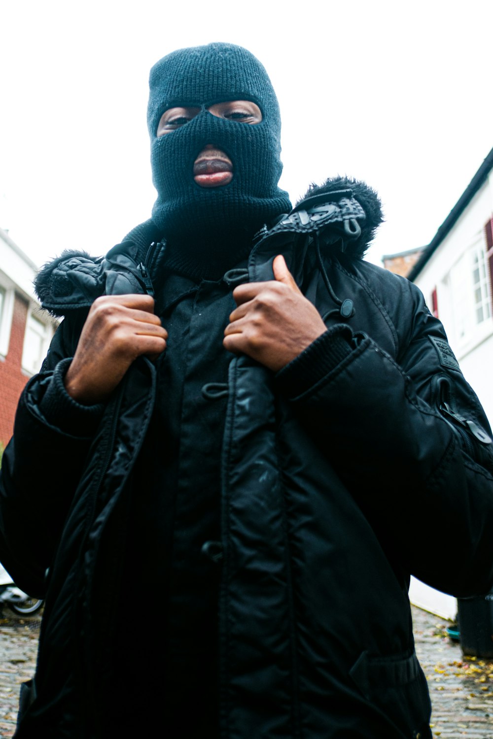 a person wearing a black coat and mask