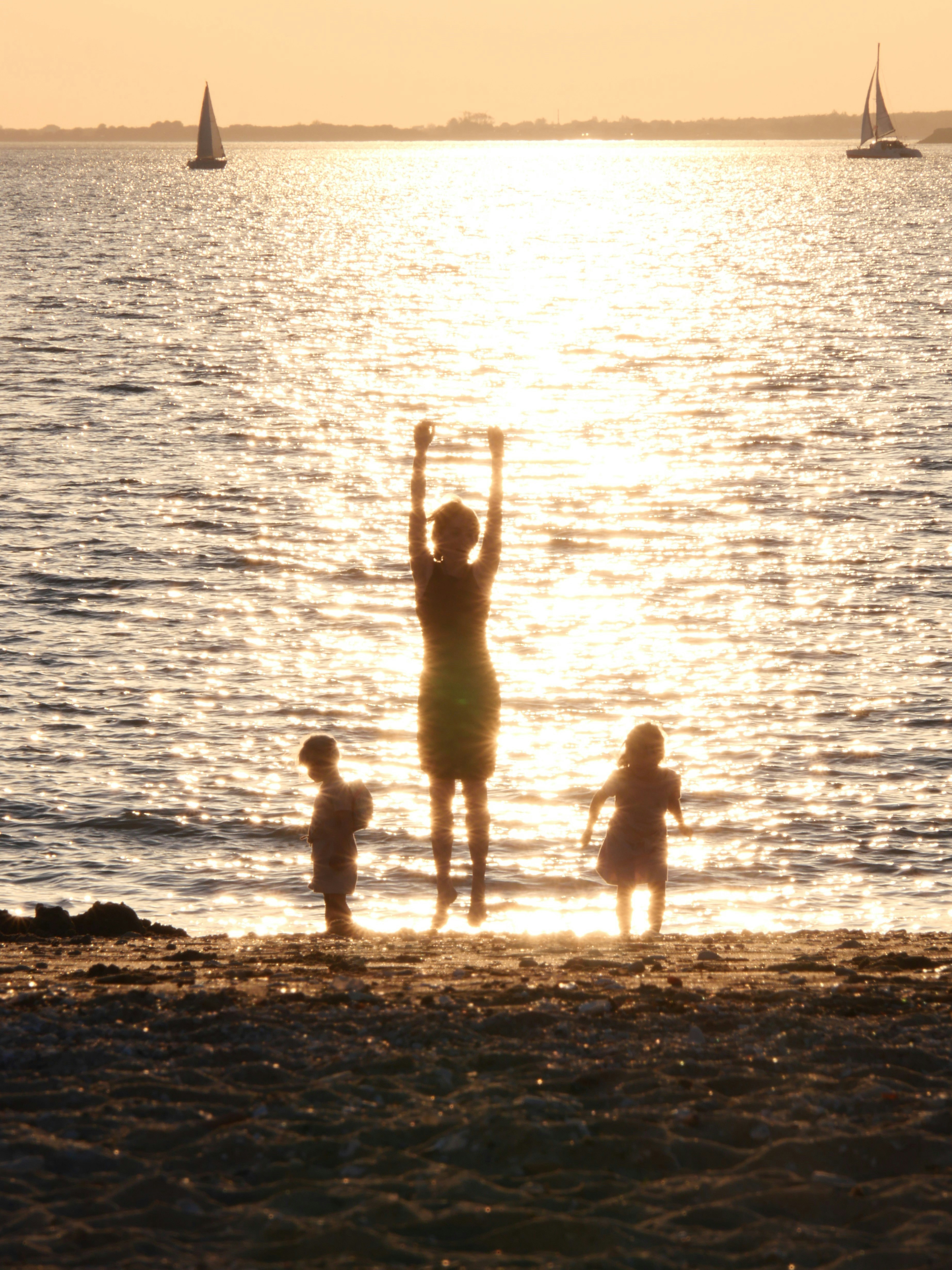 a group of people standing on a beach with a body of water in the background