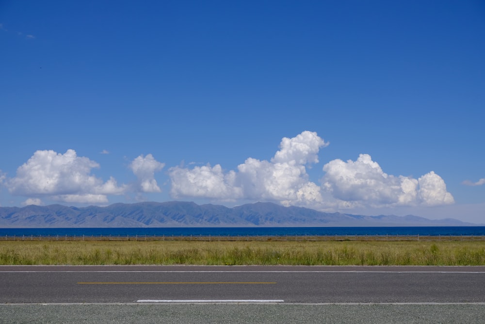 a road with grass and mountains in the background