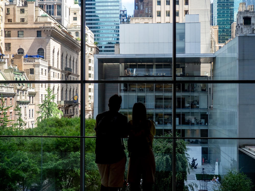 a couple of people looking out a window at a city