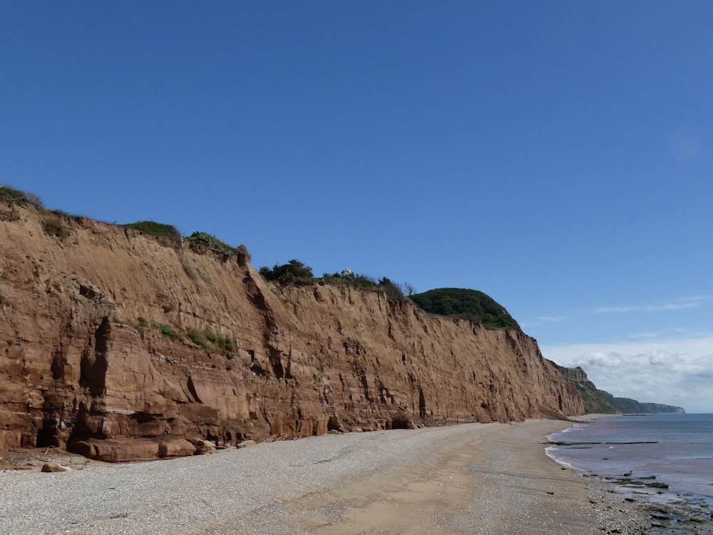 a rocky cliff next to a beach with Calvert Cliffs State Park in the background