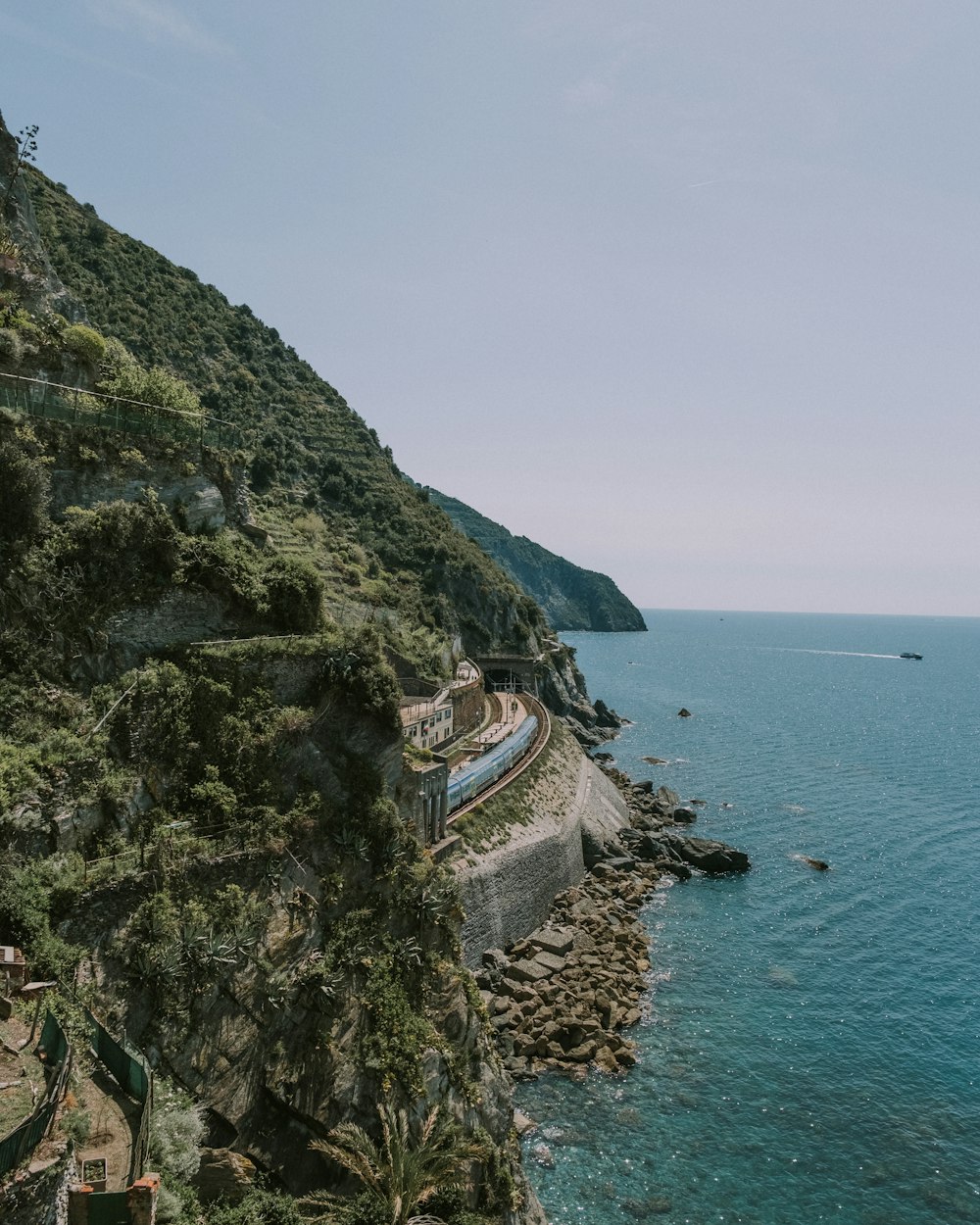 a cliff side with a building on it by the water