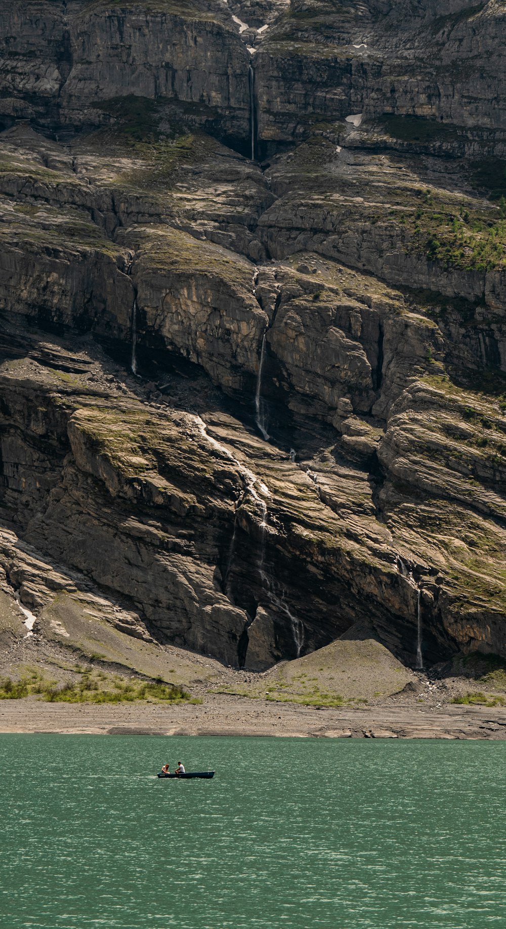 a boat in a body of water by a cliff