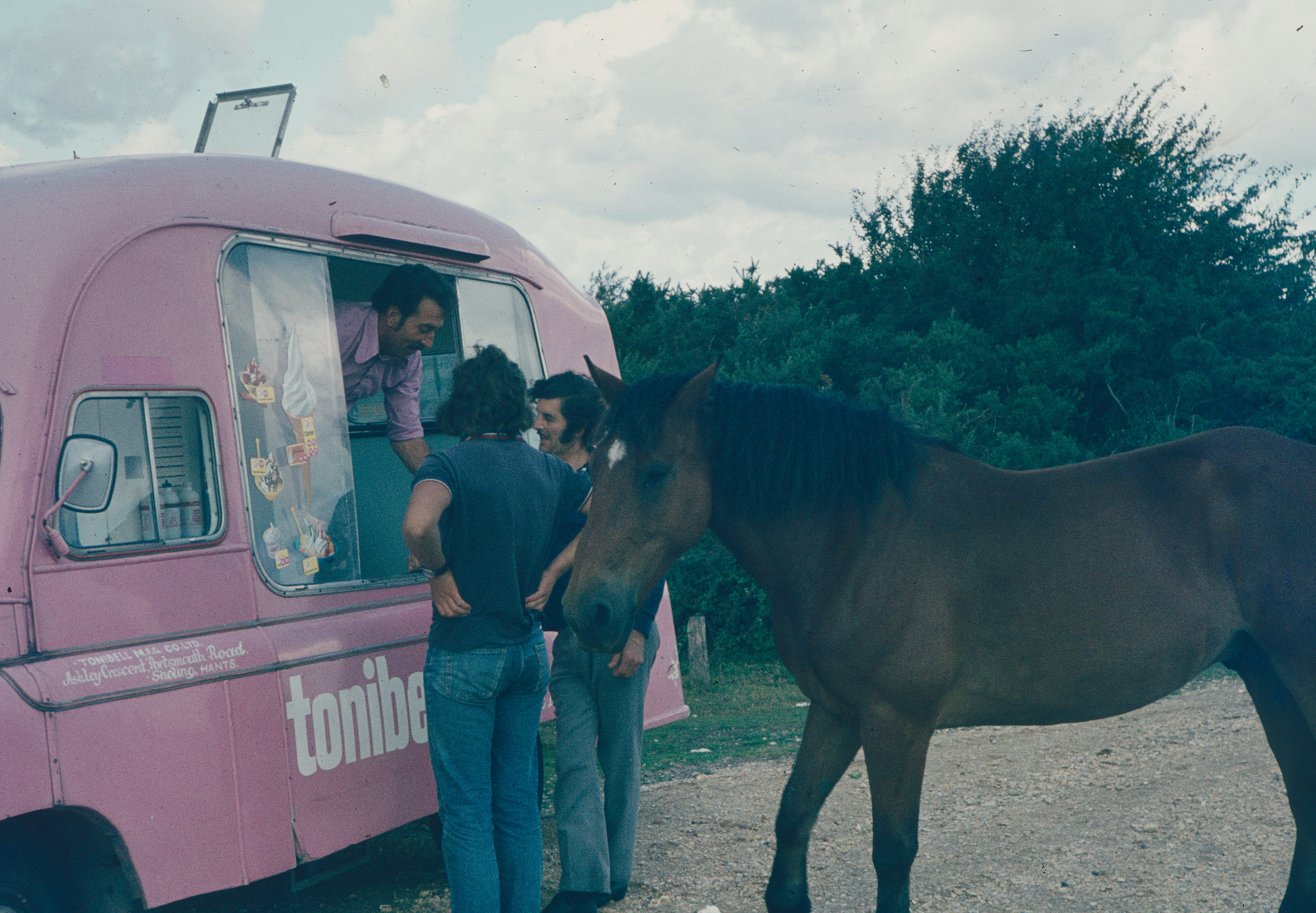 a man and a woman standing next to a horse and a van