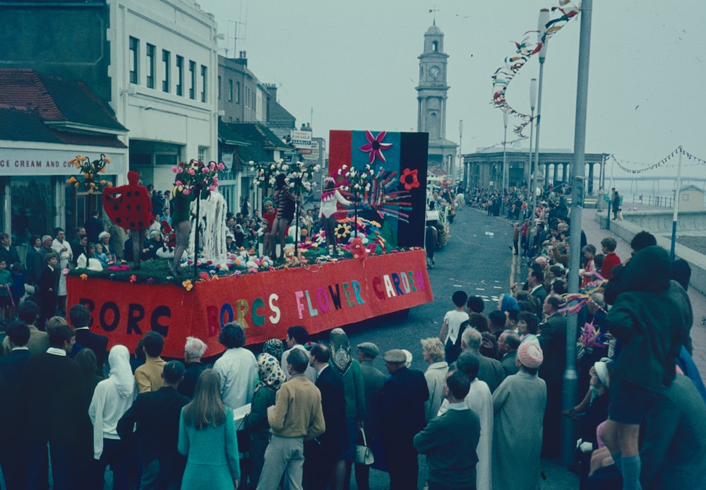 a crowd of people standing on a street with a float in the middle