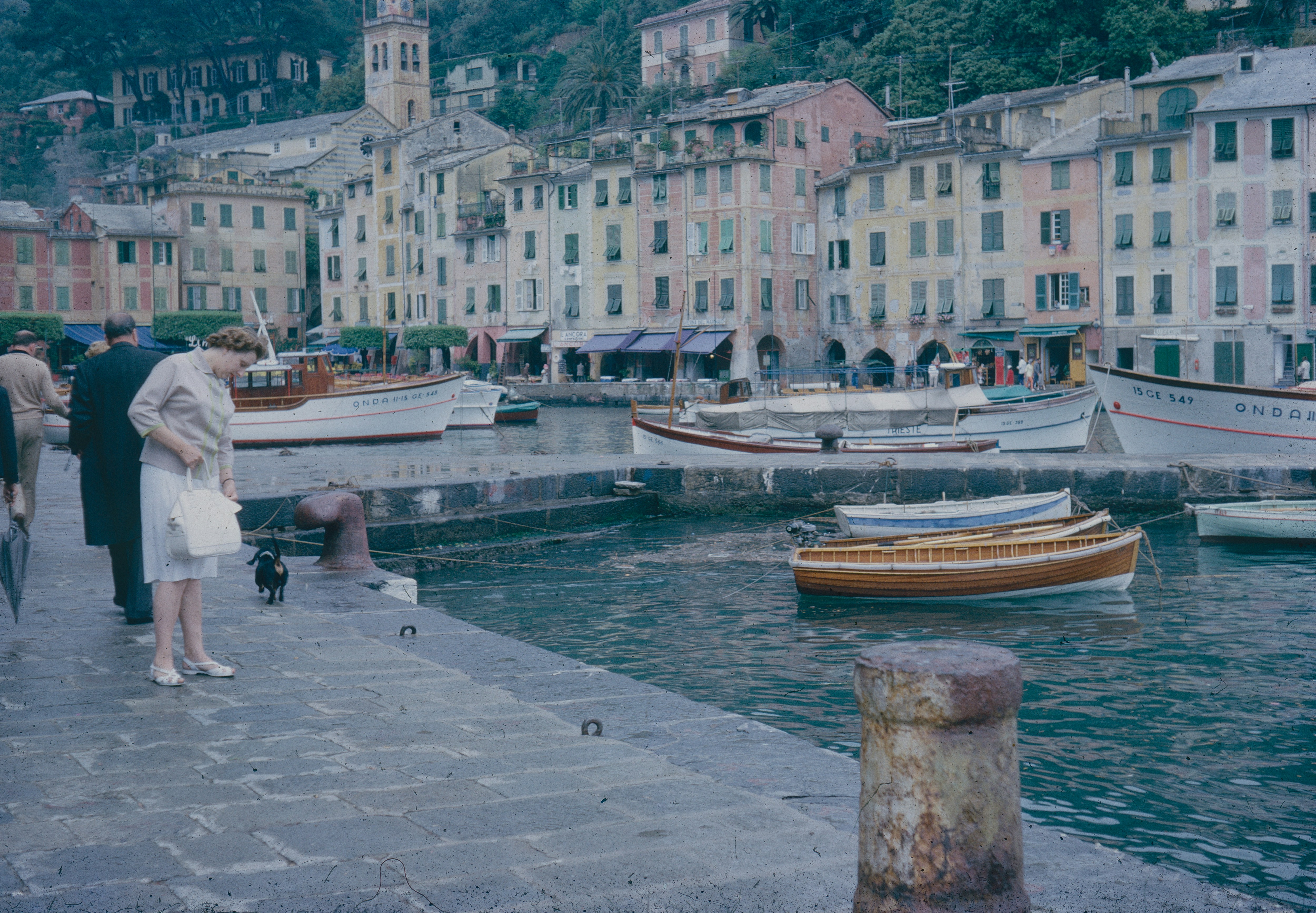 a group of people standing next to a body of water with boats in it