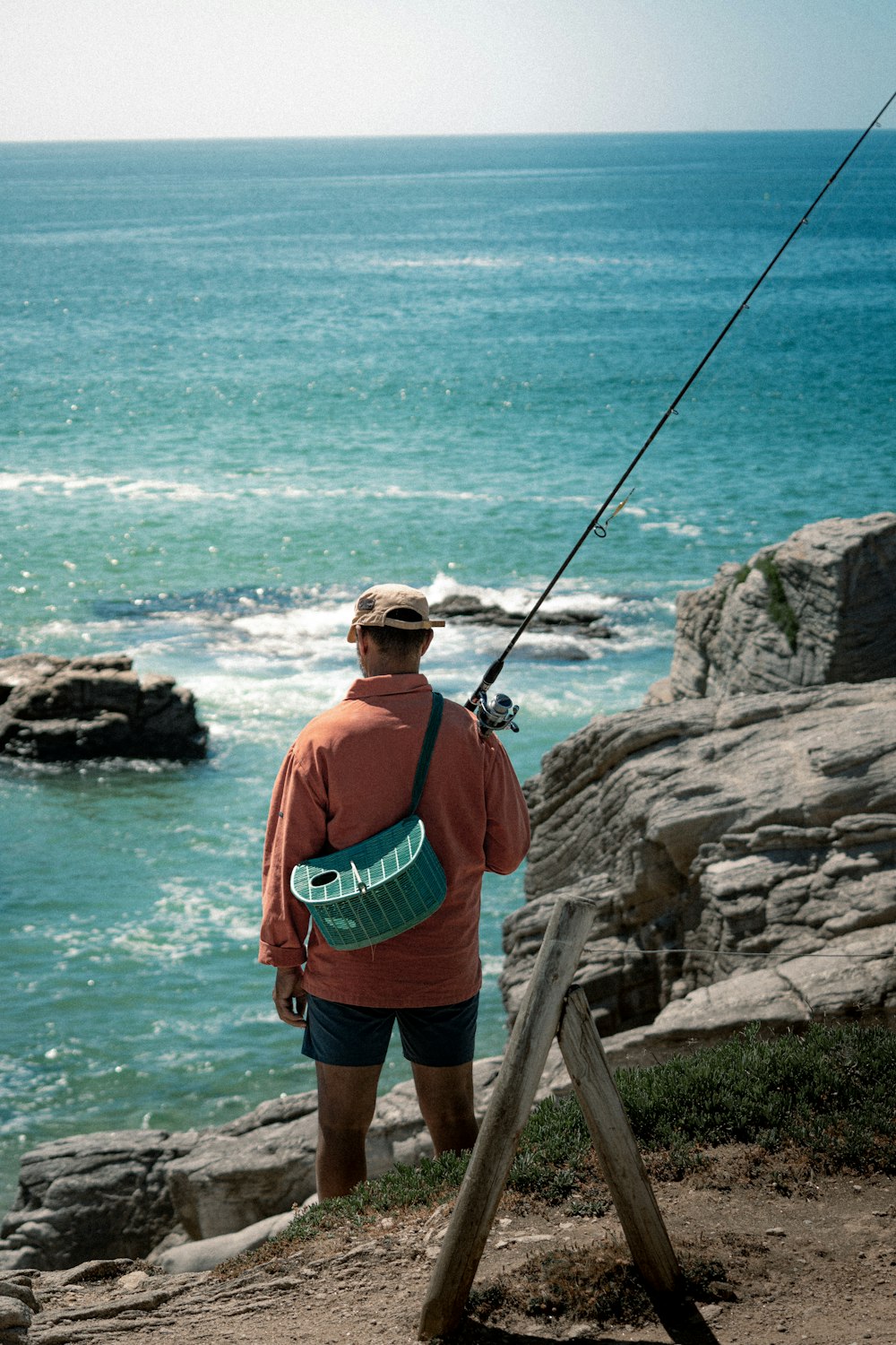 a man fishing on a rocky beach
